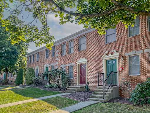 A row of red brick houses with green doors and windows.