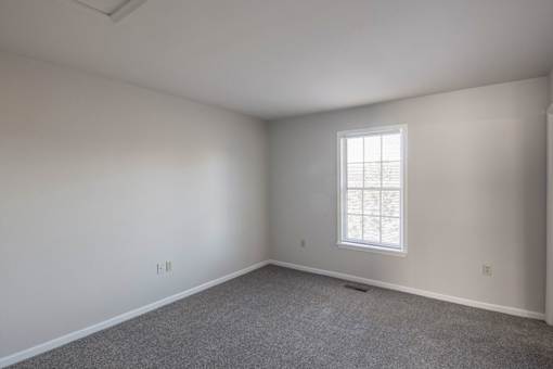 A room with a window and carpeted floor.