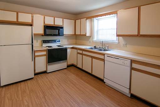 A kitchen with wooden floors and white appliances.