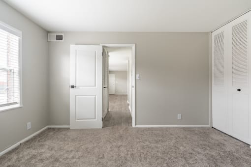 a bedroom with a carpeted floor and a door that leads to a hallway