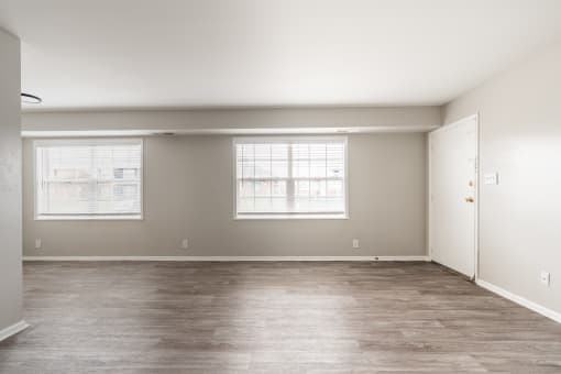 a bedroom with a hardwood floor and two windows