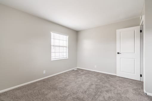 a bedroom with grey carpet and a white door