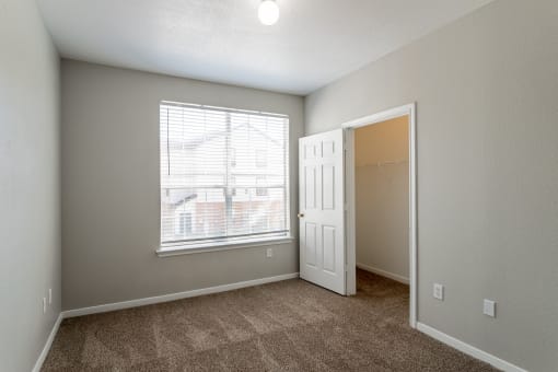 a bedroom with a large window and carpeted flooring
