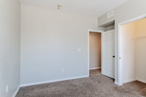 a bedroom with a carpeted floor and a closet with a door open