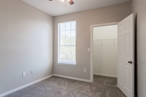 a bedroom with a large window and a closet