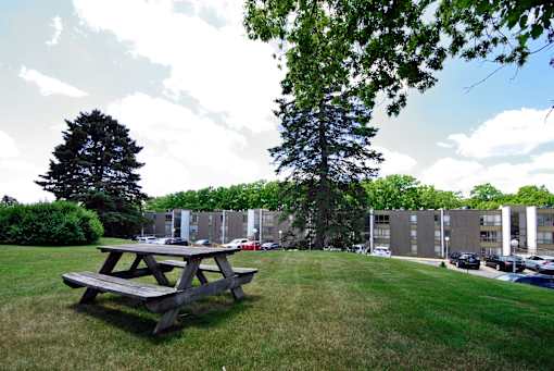 A picnic table sits in the foreground of a grassy field.