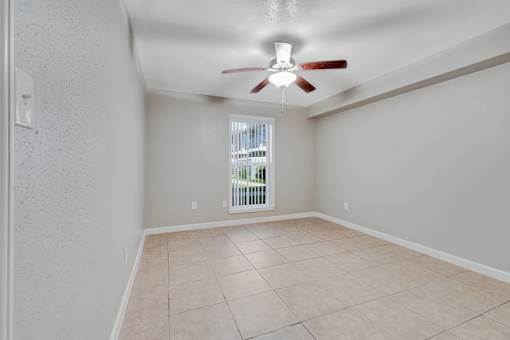 A room with a ceiling fan and tiled flooring.