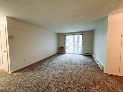 an empty living room with a door to a balcony