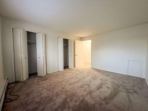 an empty living room with a carpeted floor and closet doors