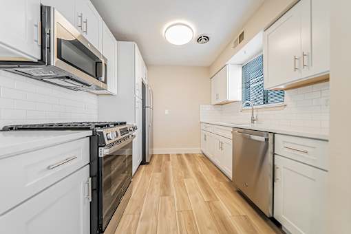 A kitchen with white appliances and wooden floors.