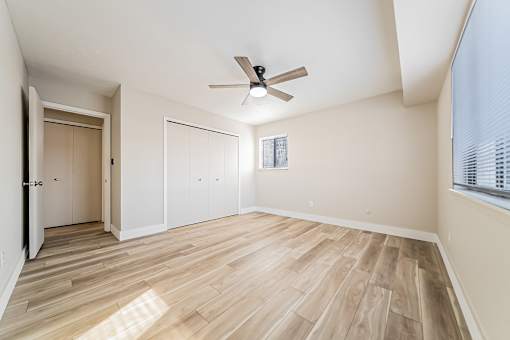A room with a ceiling fan and wooden flooring.
