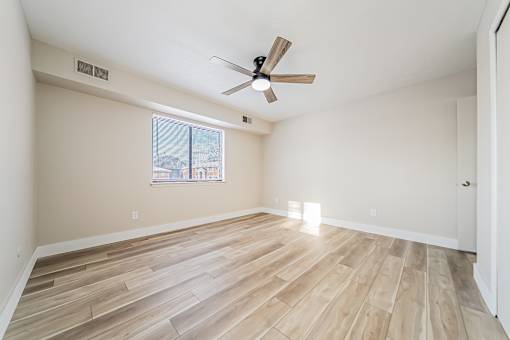 A room with a ceiling fan and wooden flooring.