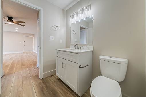 A white bathroom with a toilet, sink, and mirror.