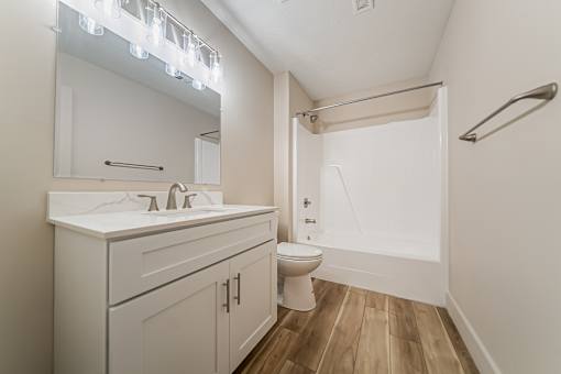 A white bathroom with a toilet, sink, and mirror.