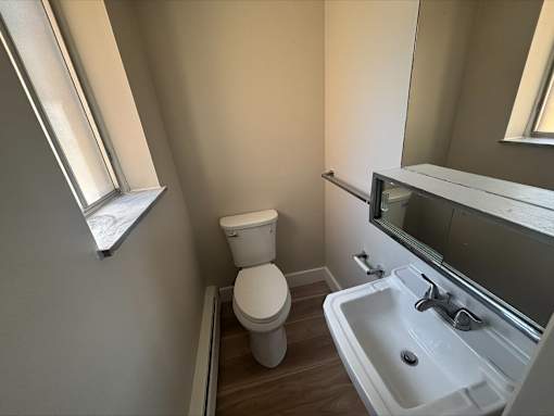 A bathroom with a toilet, sink, and mirror.