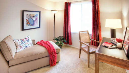 A living room with a beige couch, a chair, a table with a lamp, and a painting on the wall at Hummingbird Pointe & The Gardens, Parma