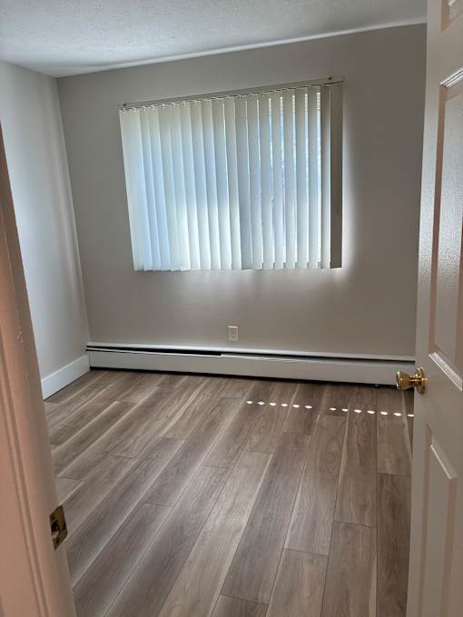 A room with wooden flooring and a window.