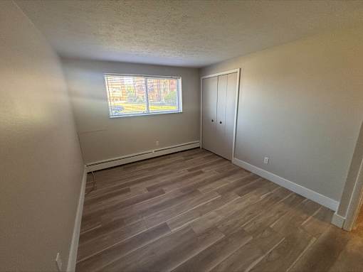 A room with a window and a wooden floor.