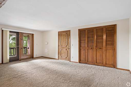 A room with a carpeted floor and a sliding glass door.
