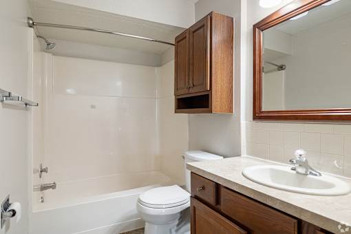 A white bathroom with a toilet, sink, and bathtub.