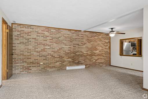 A room with a brick wall and a ceiling fan.