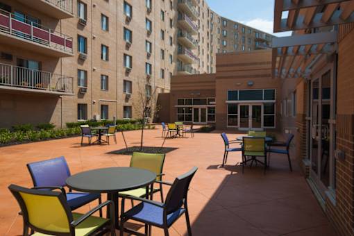 A patio with a table and chairs is surrounded by apartment buildings at Hummingbird Pointe & The Gardens, Ohio 44129