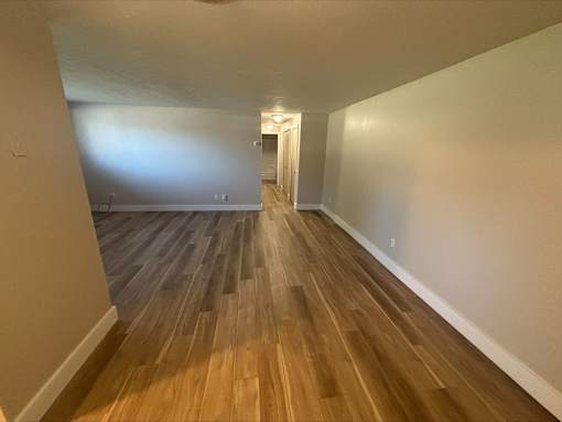 A long hallway with wood flooring and white walls.