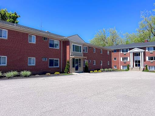 A large red brick building with a parking lot in front. at Hallwood Manor Apartments, Mentor, 44060
