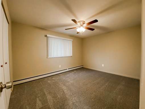 the spacious bedroom with carpet and a ceiling fan