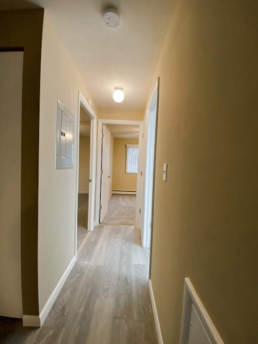 a view of a hallway with plank floors and a door to a bedroom