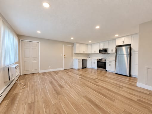 A kitchen with white cabinets and a wooden floor.