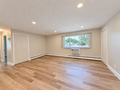 A room with wooden flooring and a window with blinds.