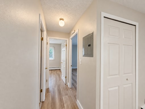 A hallway with a white door on the right and a light on the ceiling.