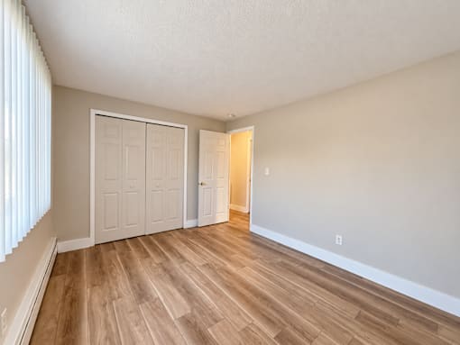 A room with wooden flooring and two doors.