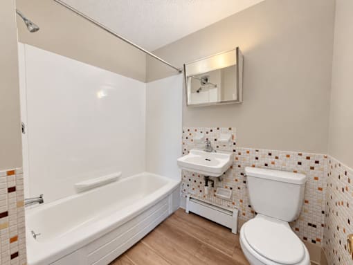 A white bathroom with a tub, toilet, and sink.