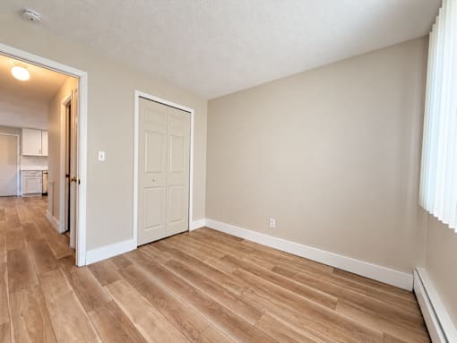 A room with a white door and wooden flooring.