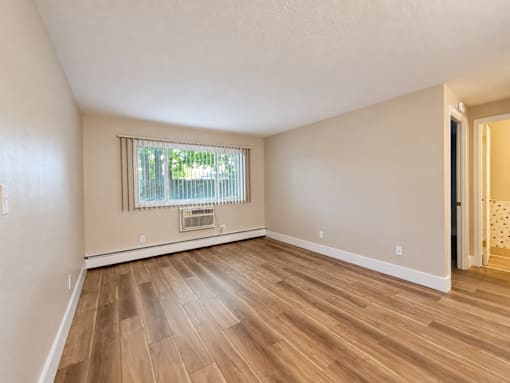 A room with wooden flooring and a window with blinds.