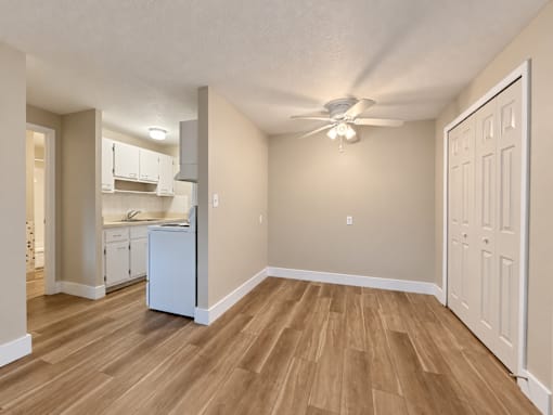 A kitchen with a refrigerator, cabinets, and a ceiling fan.