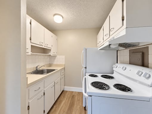 A small kitchen with a white stove and white cabinets.