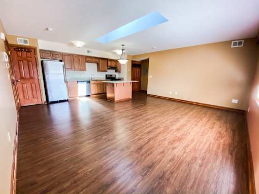 an empty living room and kitchen with wood flooring