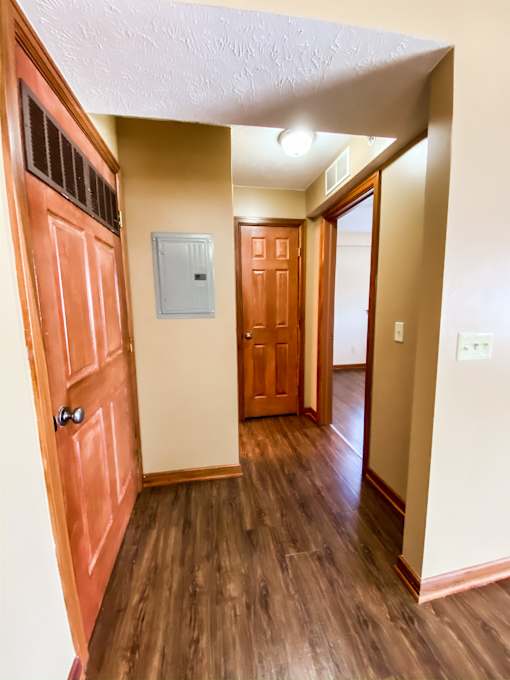 an empty hallway with a wooden door and a door to a bedroom and a hallway