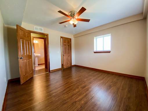 an empty bedroom with wooden floors and a ceiling fan
