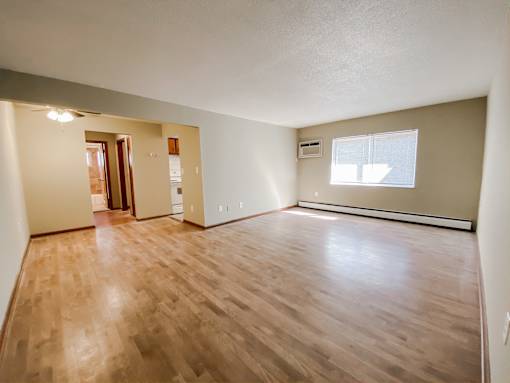an empty living room with wood floors and a window