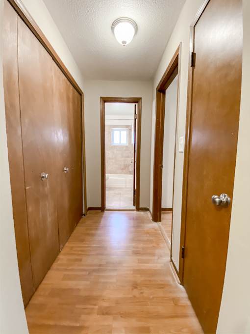 a long hallway with wooden doors and a door to a bathroom