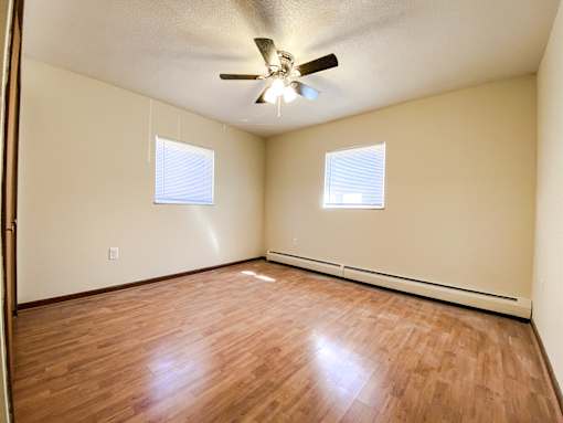 an empty bedroom with wood floors and a ceiling fan