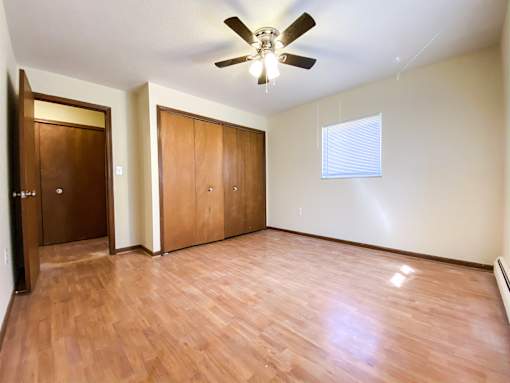 an empty bedroom with wooden floors and a ceiling fan