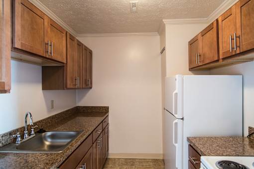 A kitchen with brown cabinets and a white refrigerator at Hummingbird Pointe & The Gardens, Parma, Ohio