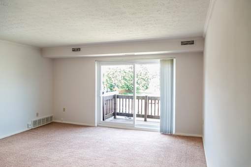 A room with a carpeted floor and a view of a balcony with a railing at Hummingbird Pointe & The Gardens, Parma, OH