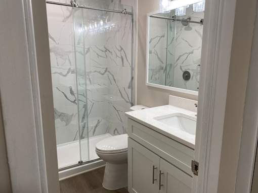 A white bathroom with a marble shower.