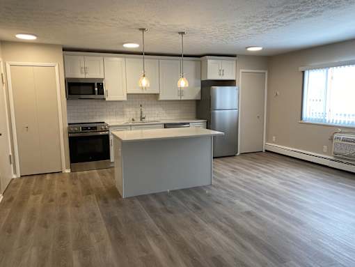A kitchen with a white island and wooden floors.